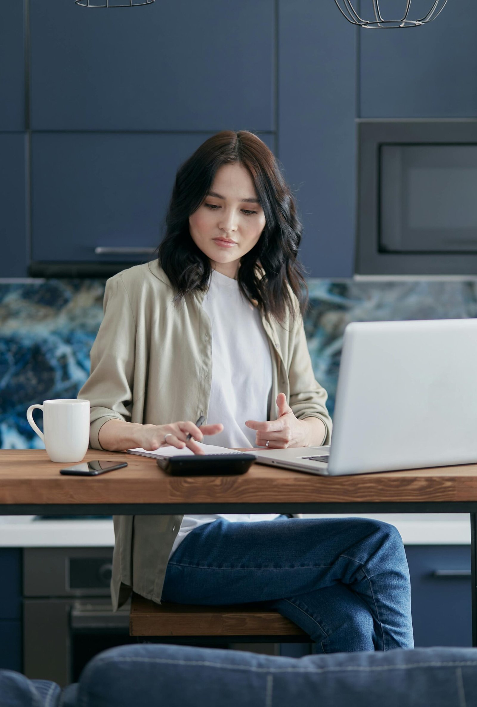 A young person sitting at a desk, reviewing their budget on a laptop